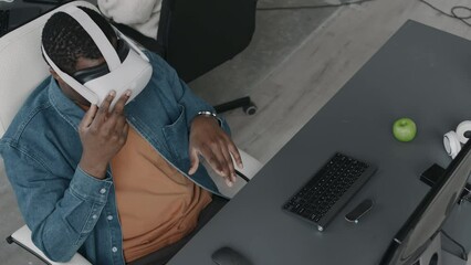 Wall Mural - from above slowmo shot of black man making typing gestures with his hands in air while sitting in vr