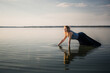 © Hanna - A beautiful young woman in a dress stands on all fours in the water in a sexy pose. Copy space. Fashion concept. Energy of water, earth and sun. Dedication. Witch ritual. State of pleasure and bliss