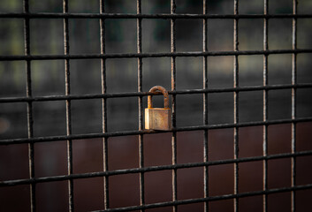 rusty and aged padlock on a meshed grill from an industrial site representing a romance relationship
