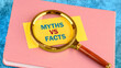 © Ihar - Business, financial and fact vs myth concept. Copy space. Concept words, symbol Fact vs myth on a yellow business card with a magnifying glass on top