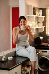 Canvas Print - Portrait, home and woman with coffee, smile and relax with break, cappuccino and espresso. Face, person and girl in kitchen, chilling and enjoy morning tea with latte, comfort and sitting on counter