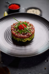 Wall Mural - Tuna and avocado tartare on a dark ceramic plate