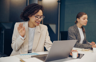 Wall Mural - Young female freelancer talking with colleague via video call while sitting in modern coworking
