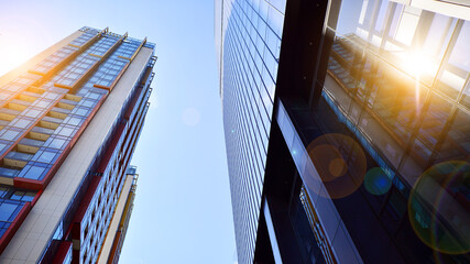 Bottom view of modern skyscrapers in business district against blue sky. Looking up at business buildings in downtown.