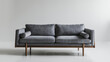© Design Mania - A stylish grey couch with wooden legs and frame, against a clean white backdrop.