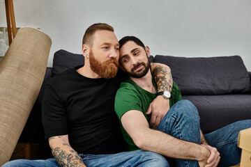 Sticker - A couple of men sit comfortably on top of a couch in their new home