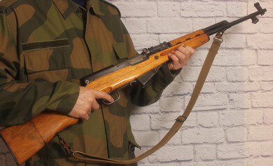 a man wearing a helmet holds his rifle in a room