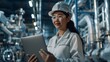 © Bundi - Asian female engineer in white hardhat, focused on computer screen at electronic manufacturing factory.