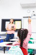 © WavebreakMediaMicro - A biracial female teacher holds tablet, student raises her hand, copy space