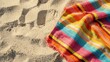 © Artyom - Colorful striped blanket on sandy beach background
