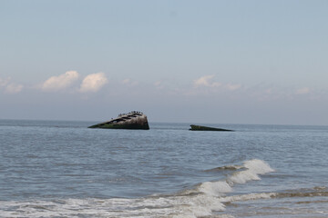 Wall Mural - This is a picture of the sunken ship off the coast of Sunset beach in Cape May New Jersey. The rusty metal hull coming out of the ocean. The brown vessel is not a habitat for shorebirds.