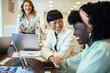 © Marko Geber - Multiethnic female colleagues discussing work with laptops in a modern office