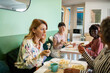 © Marko Geber - Diverse female employees eating lunch together in office