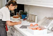 © peopleimages.com - Woman, kitchen and package cupcakes order for customer or client, homemade treats and startup bakery business. Girl, home and writing for delivery information or ingredient list, dessert and prepare.