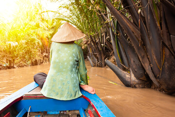 Wall Mural - Woman with asian hat rowing in a boat on jungle river