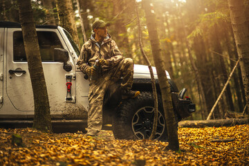 Caucasian Hunter Sitting on SUV offroad vehicle