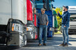 © Tomasz Zajda - Two Truckers Standing Next to a Row of Semi Trucks