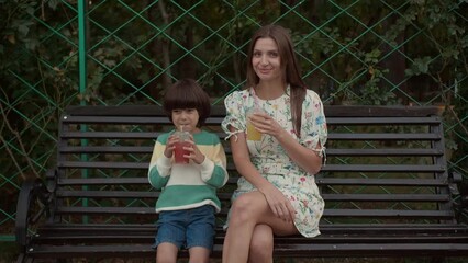 Sticker - Little boy and his mother drinking lemonade on bench in park