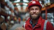 © Adi - Shot of a handsome young bearded factory worker in uniform holding protective hardhat smiling joyfully to the camera posing
