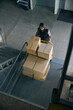 © Viacheslav Yakobchuk - Freight handler transporting goods on wheeled cart in warehouse facility
