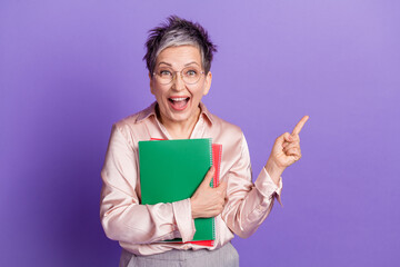 Sticker - Photo portrait of lovely senior lady point empty space hold papers dressed stylish satin garment isolated on violet color background