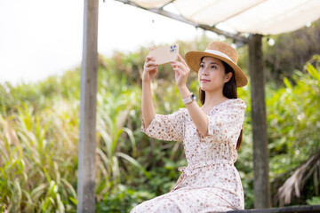 Canvas Print - Woman with straw hat and use mobile phone to take photo at outdoor