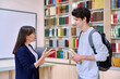 © Valerii Honcharuk - Female teacher talking to guy teenage college student inside educational library office