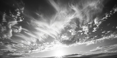 Wall Mural - A black and white photo of a cloudy sky with a sun shining through the clouds. Scene is serene and peaceful, as the sun's rays break through the clouds, creating a warm and inviting atmosphere