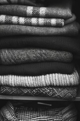 Wall Mural - A pile of black and white sweaters stacked on top of each other. The sweaters are all different colors and styles, but they all have a similar texture and feel. Concept of warmth and comfort