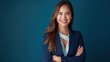 © Ron - Portrait of smiling business woman in blue suit standing with arms crossed on dark background, confident female executive looking at camera isolated over deep sea color background