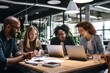 © SaroStock - a group of people sitting around a table with laptops, A gathering of individuals seated at a table, each with their own laptop.