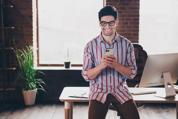 Wall Mural - Photo of nice young corporate man use smart phone wear striped shirt loft interior office indoors