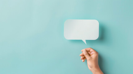 Simple composition featuring a hand holding an empty speech bubble against a soft blue background