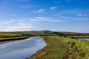 Wall Mural - A pathway running alongside the Cuckmere River in the South Downs, with a blue sky overhead