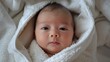 © pngking - New Asian newborn baby wearing a white towel looks pleased after bath