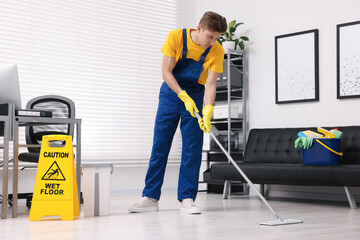 Wall Mural - Cleaning service worker washing floor with mop. Bucket with supplies and wet floor sign in office