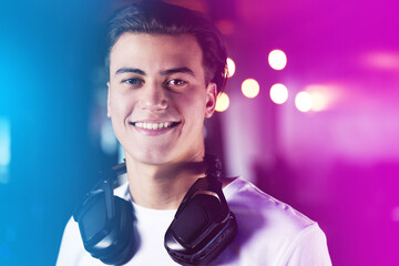 Portrait, headphones and happy gamer in neon lights, online streaming and competition for esports on internet. Virtual player, video games and streamer with smile, cyber hobby and entertainment