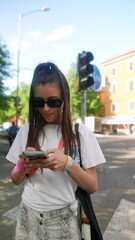 Wall Mural - A gorgeous young lady, with sunglasses on, speaks while looking into the camera on the street.