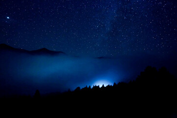 Wall Mural - Sky with twinkling stars over mountains at night