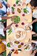 © CarlosBarquero - Vertical. Top view from above of unrecognizable people around meal table with wine glasses and food outdoors celebration terrace BBQ party. Young friends enjoying together lunch time on summer weekend