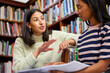© peopleimages.com - Women, tutor and student in library with books or helping for education learning, university or scholarship. Female people, smile and group project for college course on campus, friends or research
