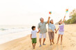 © CandyRetriever  - Happy Asian family travel ocean on summer holiday vacation. Grandparents and grandchildren boy and girl enjoy and fun outdoor lifestyle walking and playing together at tropical island beach at sunset.
