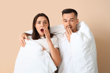 Poster - Sleepy young couple with soft blanket on beige background