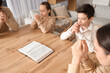 © Pixel-Shot - Family praying together with Holy Bible on table at home