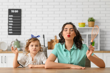 Canvas Print - Beautiful pin-up woman and her daughter with cooking utensils in kitchen