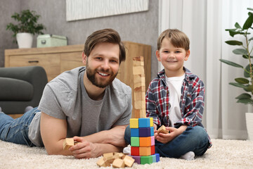 Canvas Print - Family portrait of happy dad and son near tower of cubes at home