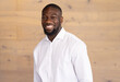 © Wavebreak Media - At modern office, young African American man smiling in front of wooden background