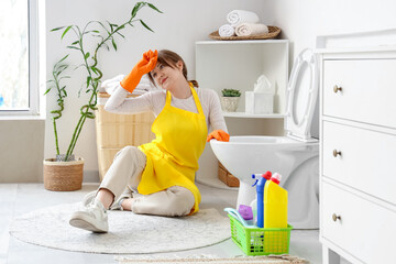 Canvas Print - Young woman tired after cleaning toilet bowl in modern bathroom