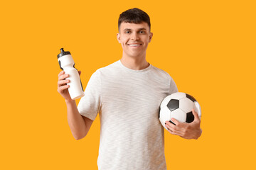 Sticker - Sporty young man with bottle of water and soccer ball on yellow background