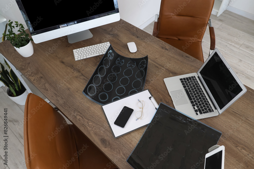 X-ray images with modern gadgets on table in medical office, top view